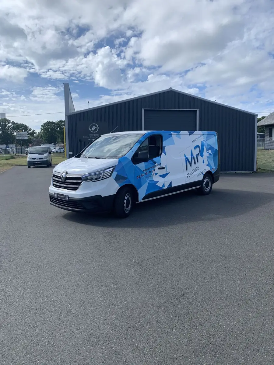 Marquage de véhicule utilitaire Renault Trafic bleu et blanc devant l'atelier Armor Design à Morieux
