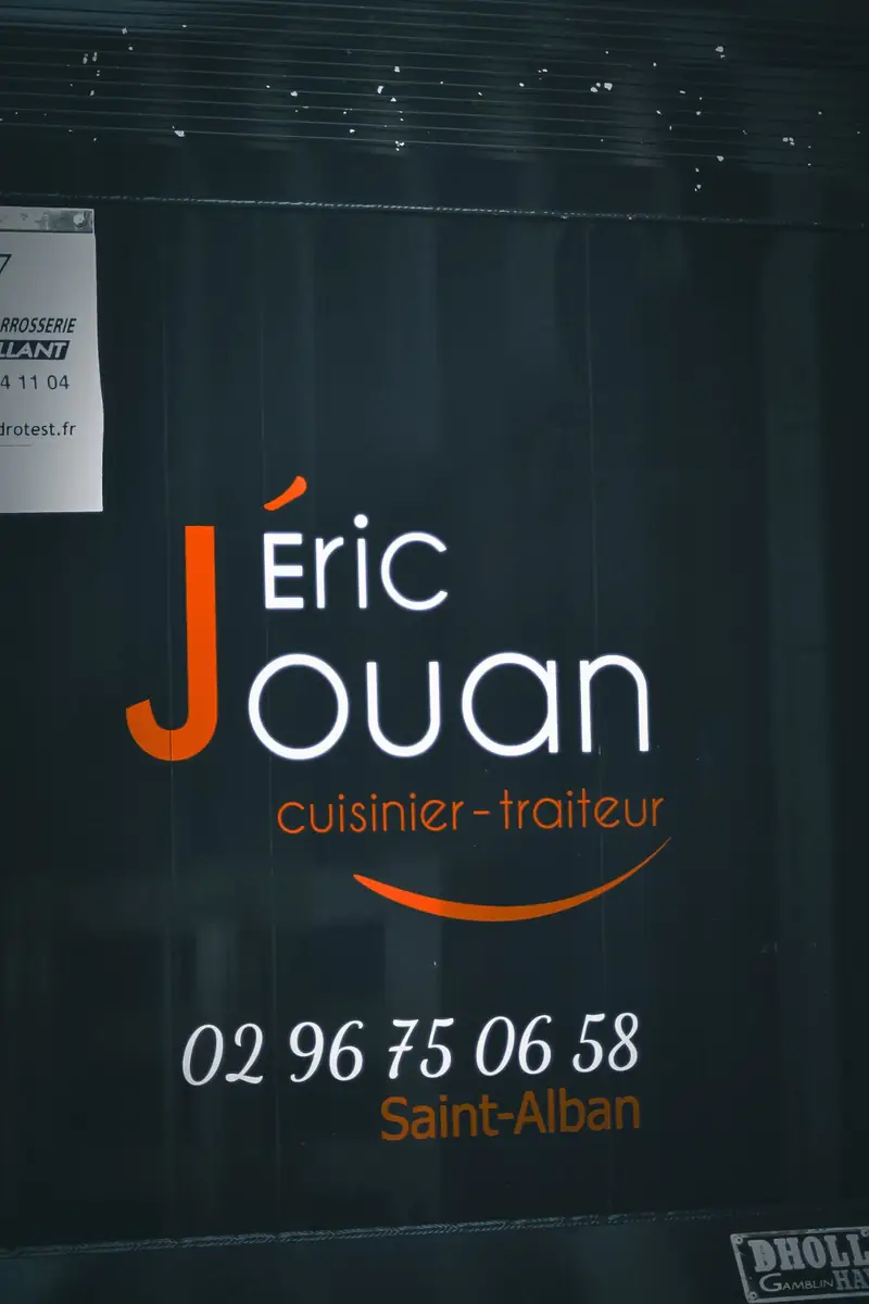 Détail d'un lettrage adhésif orange et blanc sur carrosserie noire