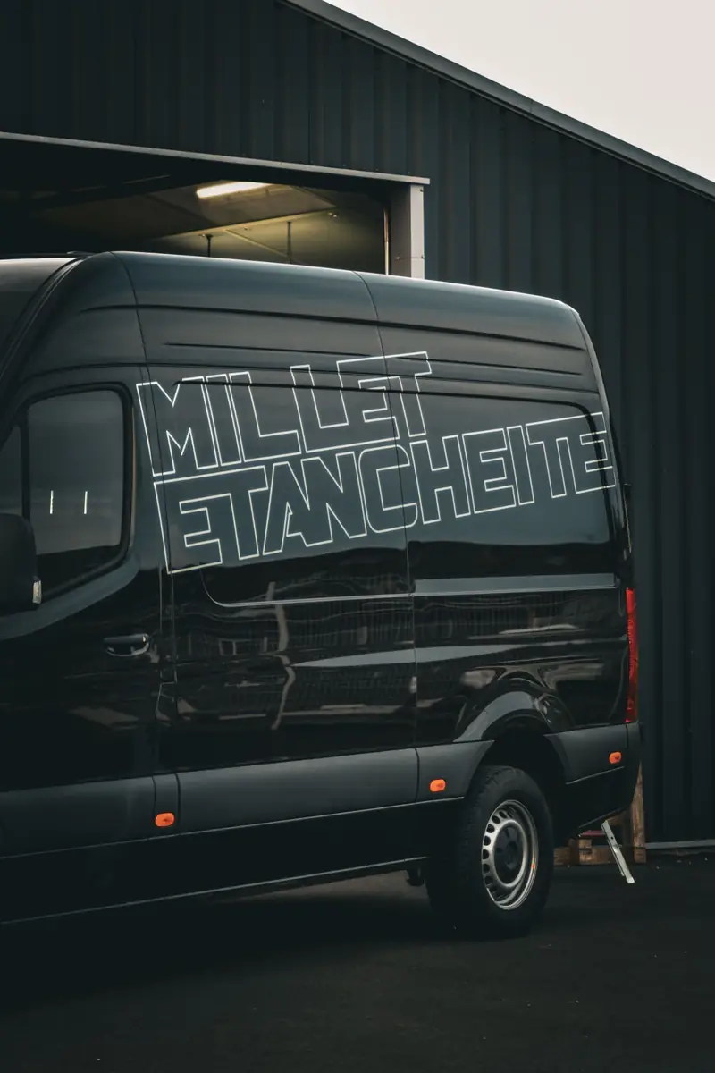 Autocollant publicitaire blanc posé sur un véhicule utilitaire noir