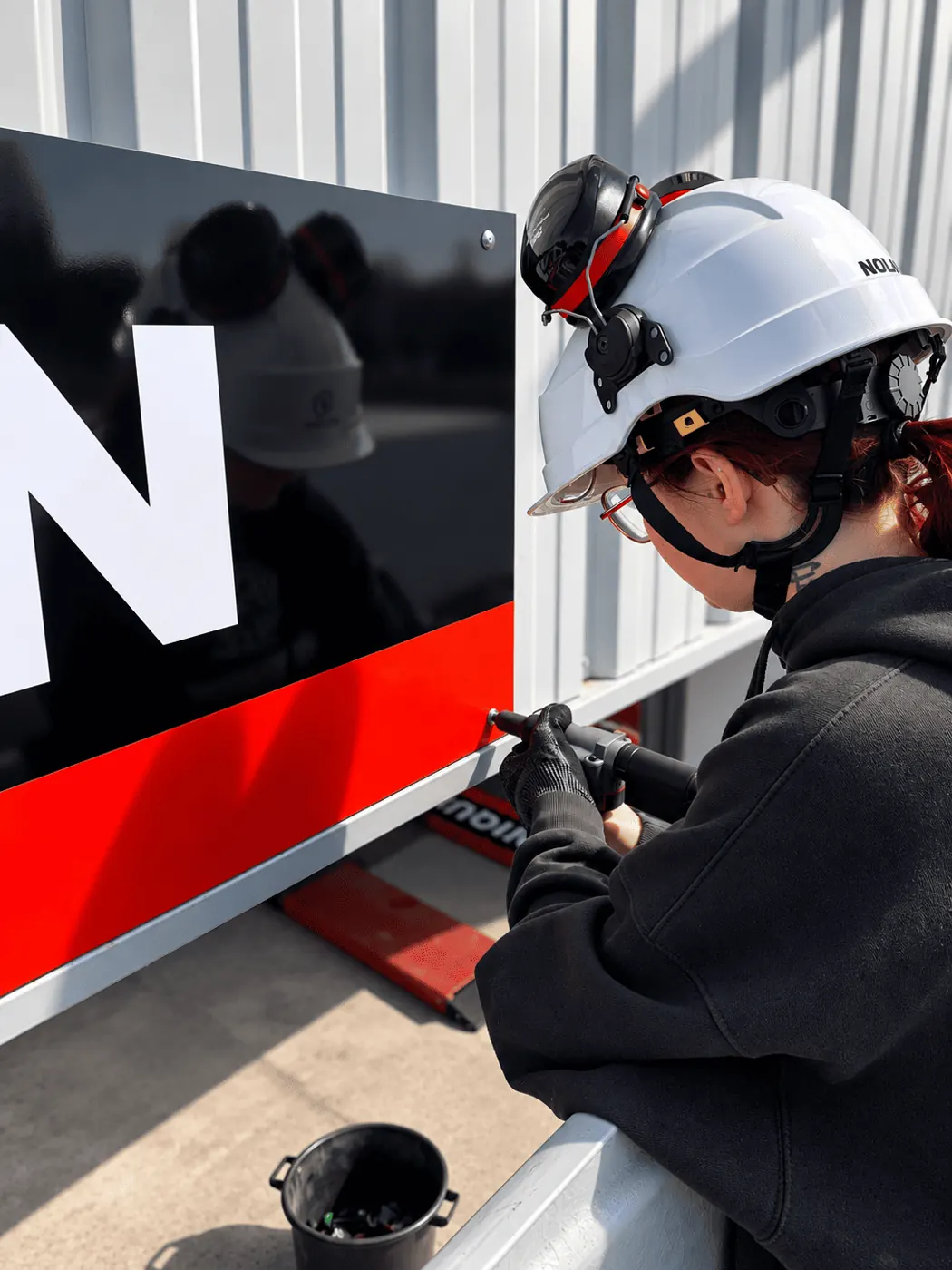 Enseigniste Armor Design posant un panneau d'enseigne sur un bâtiment professionnel